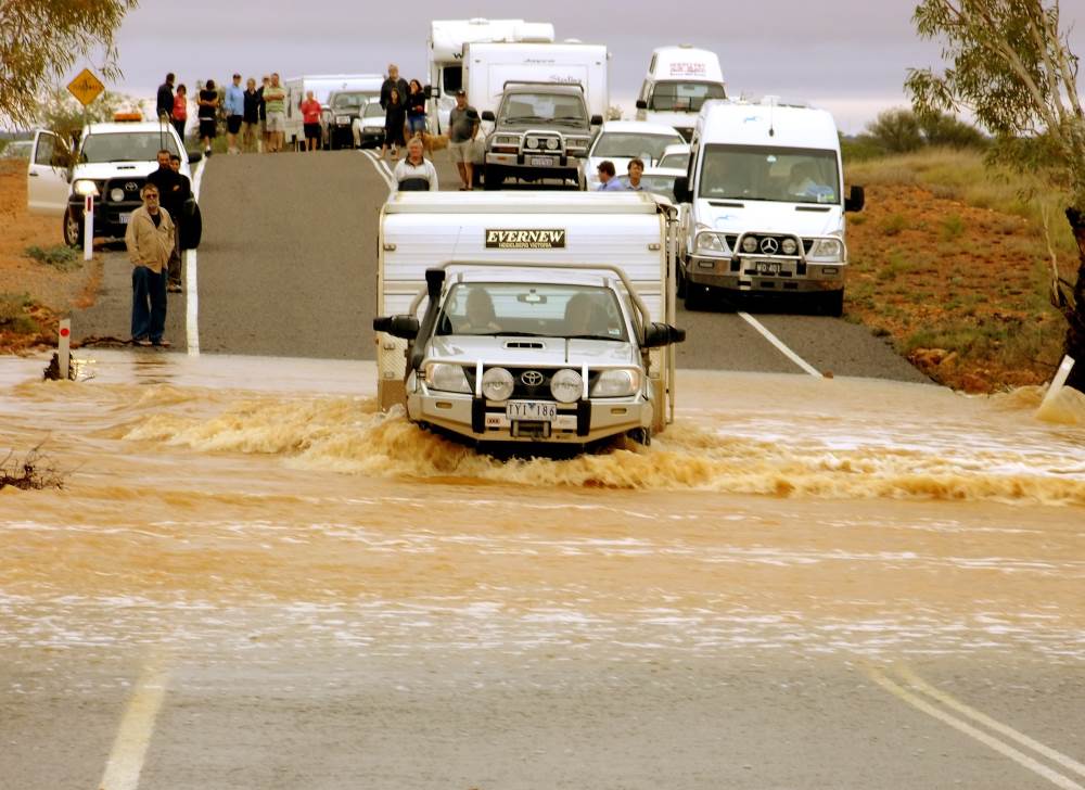 ute towing caravan crosses flooded stream
