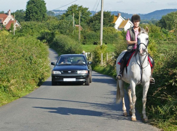 Car approaching horse and rider from behind