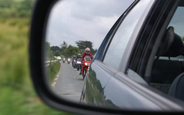 bikers form a queue behind a slow-moving car
