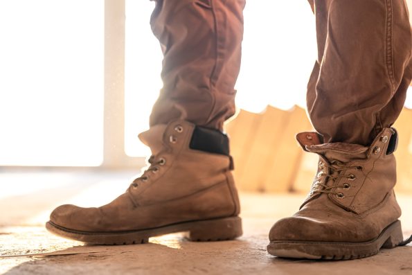 Close-up of rugged safety boots worn by a construction worker on a job site with sunlight in the background.